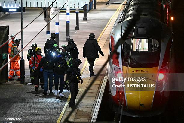 Police and British Transport Police officers walk on the platform alongside an LNER Azuma train at Huntingdon Station in Huntingdon, eastern England,...