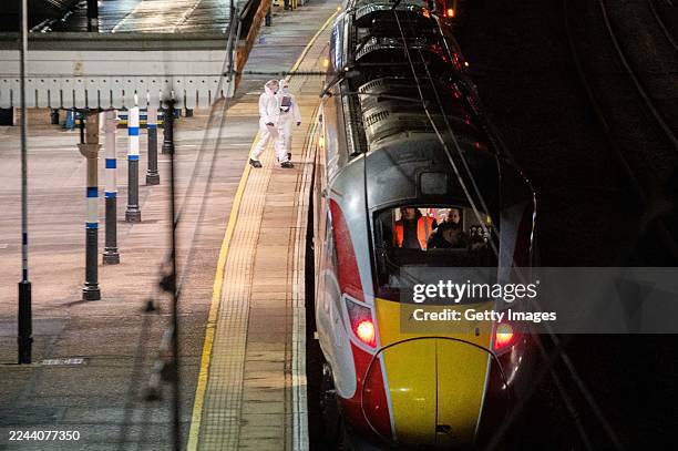 Crime scene investigators walk along a train platform at Huntingdon Station on November 2, 2025 in Huntingdon, England after a stabbing attack on a...
