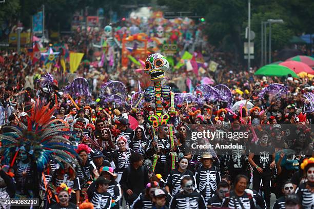 People dressed in costumes take part in the annual Day of the Dead parade while holding a skeleton figure along the main avenues in the city center,...