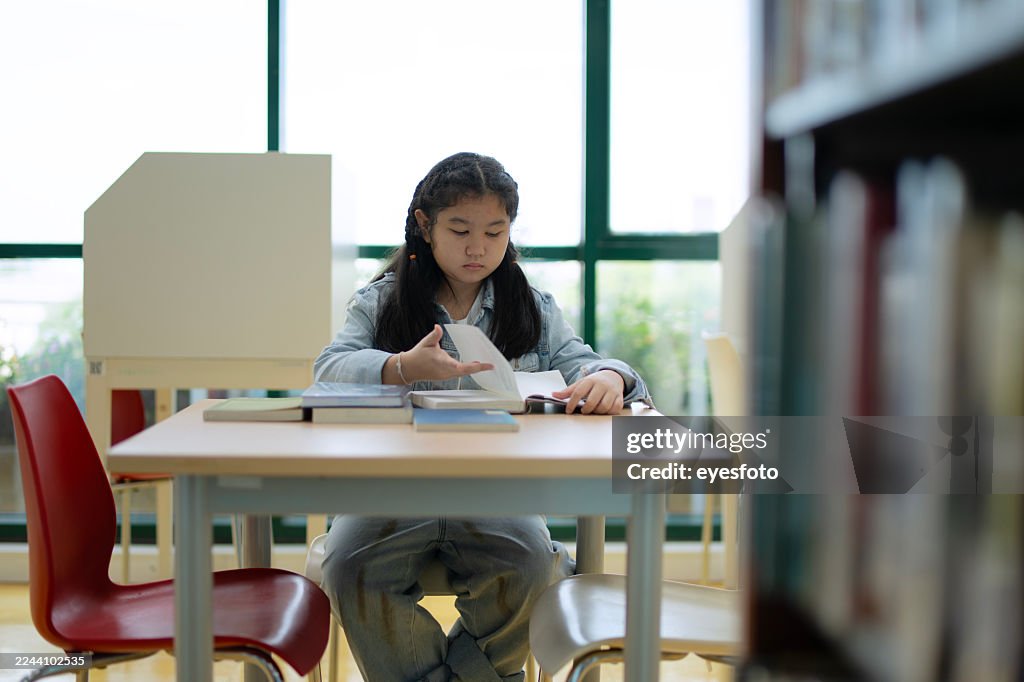 A young girl is reading the book at the library.