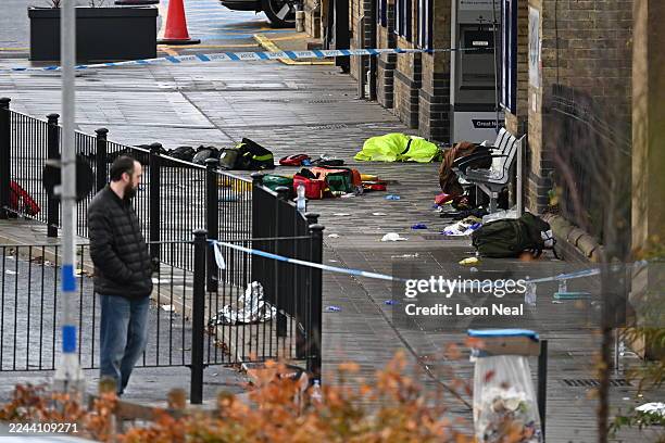 Man stands outside Huntingdon Station as Police and other emergency responders attend the scene on November 02, 2025 in Huntingdon, England after a...