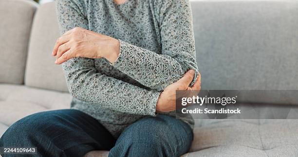 dolor de manos, mujer mayor y codo en el sofá con artritis, esguince de lesión e inflamación muscular. jubilación, persona mayor y dolor articular en casa con compresión nerviosa, rotura de ligamentos o tendinitis - fibromialgia fotografías e imágenes de stock