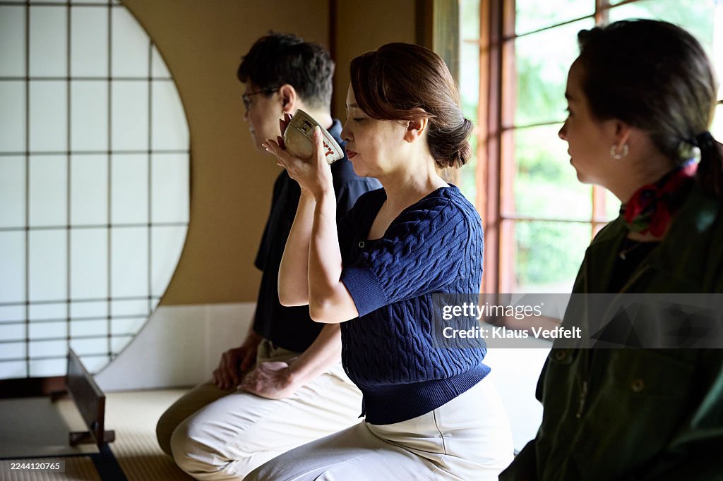 Woman drinking tea while sitting with guests