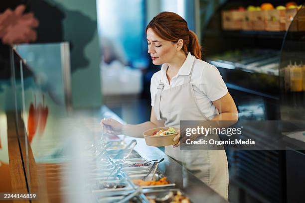 femme servant des aliments frais sains au bar à salades - libre service photos et images de collection