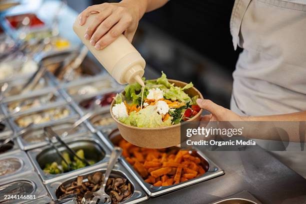 worker preparing healthy take-out salad with dressing - salad bowl stock pictures, royalty-free photos & images