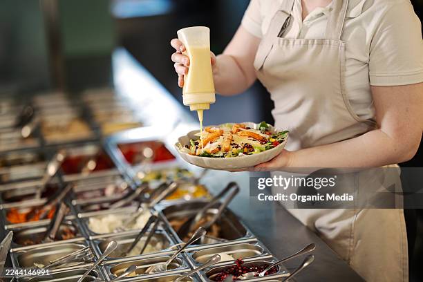 chef adding dressing to fresh mixed salad - salad dressing stock pictures, royalty-free photos & images