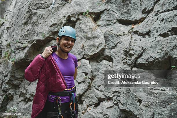 female rock climber in helmet puts her arm out after reaching limestone wall - rock face stock pictures, royalty-free photos & images