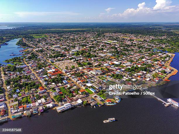 aerial view of a vibrant townscape nestled by a river against a bright blue sky,terra santa,brazil - manaus stock pictures, royalty-free photos & images