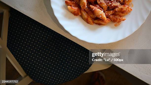 high angle view of a plate of gnocchi with tomato sauce and parmesan cheese on a table - midday stock pictures, royalty-free photos & images
