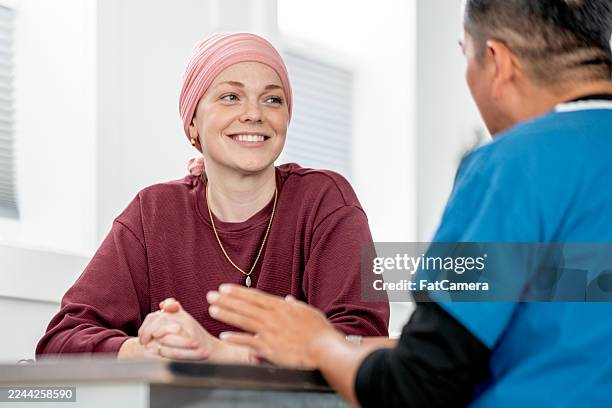 friendly conversation between patient wearing hijab and healthcare professional in a modern clinic - oncologist stock pictures, royalty-free photos & images