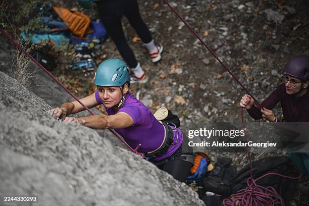 female climbers teamwork on a mountain rock climb with helmets and ropes - outdoor adventure in nature - rock face stock pictures, royalty-free photos & images