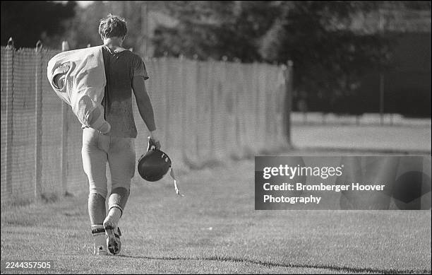 View, from behind, of an unidentified San Jose State University football player, carrying his pads over one shoulder and his helmet in his other...