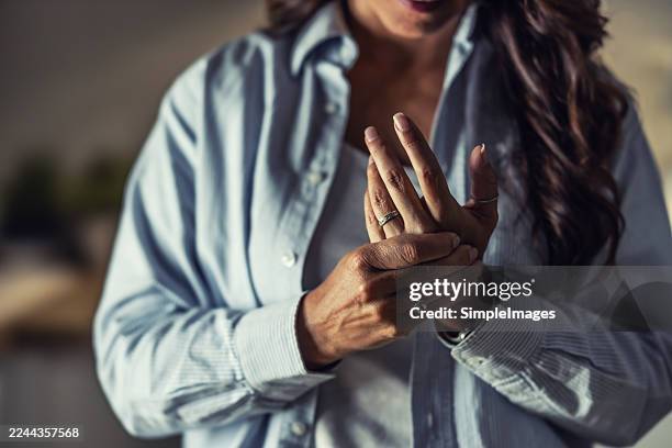 a woman holds her wrist, a classic gesture indicating pain in the joints, tendons, or muscles, which can be a symptom of various conditions, such as sprains or strains. it could also be a carpal tunnel blockage, or chronic pain from arthritis or rheumatis - neuropathy stock pictures, royalty-free photos & images