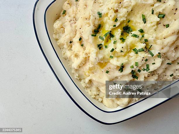 mashed potatoes with butter, chives, and black pepper in bakeware dish - mashed potatoes stock pictures, royalty-free photos & images