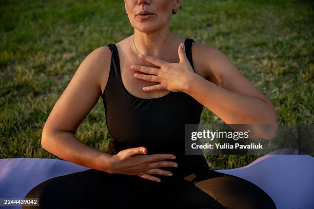woman practicing deep breathing exercise outdoors for wellness - zwerchfell stock-fotos und bilder
