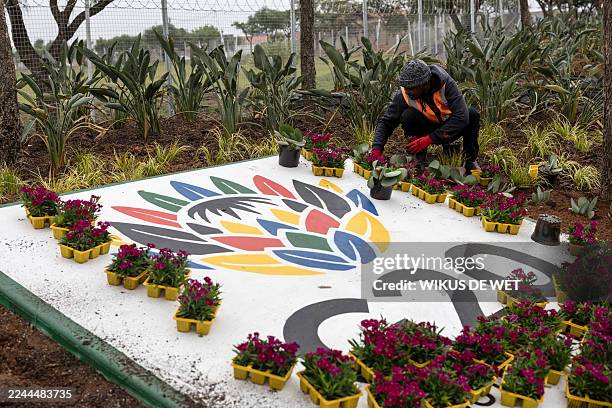 Worker plants flowers next to a G20 logo outside the NASREC Expo Centre in Johannesburg on November 4, 2025 where the upcoming G20 summit will be...
