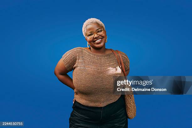 young creative black woman smiling confidently against solid blue background - voluptuous stock pictures, royalty-free photos & images