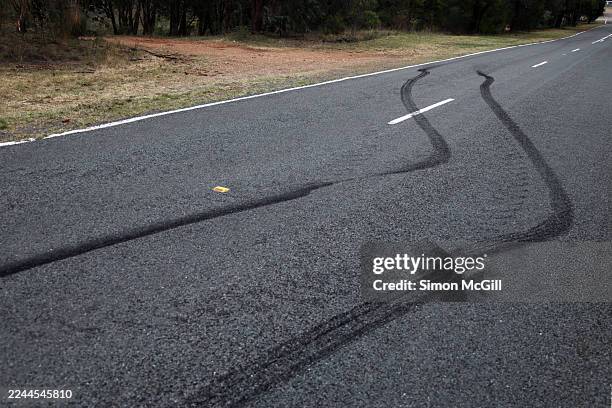 tire skid-marks swerving across both lanes of a rural road - derrapar imagens e fotografias de stock
