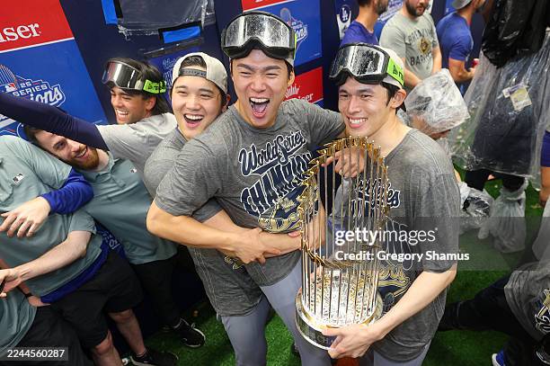 Shohei Ohtani, Yoshinobu Yamamoto, and Roki Sasaki of the Los Angeles Dodgers celebrate in the locker room after defeating the Toronto Blue Jays 5-4...