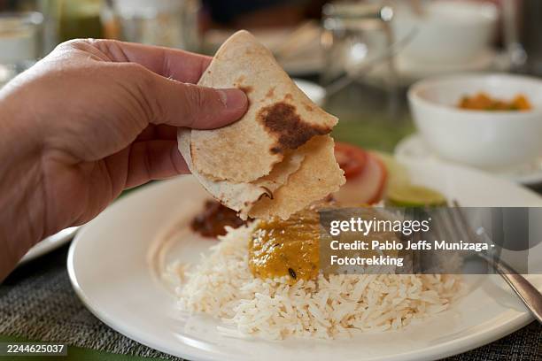 hand eating traditional nepalese dal bhat meal with flatbread - chapatti stock pictures, royalty-free photos & images