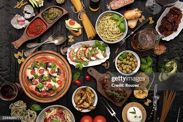 rustikales italienisches abendessen mit pizza, pasta und caprese-salat auf dunklem holztisch - italienische küche stock-fotos und bilder