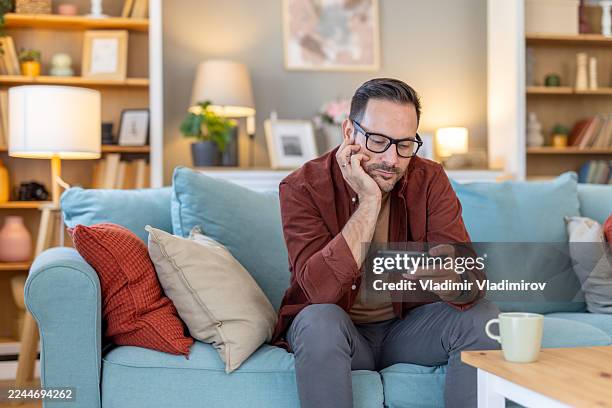 thoughtful man engaged in gameplay, focused expression - difusão de televisão imagens e fotografias de stock