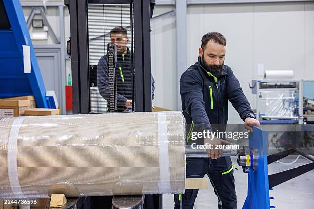 men working in production and distribution industry, using forklift and adjusting bale on axis on machine - dielectric stock pictures, royalty-free photos & images