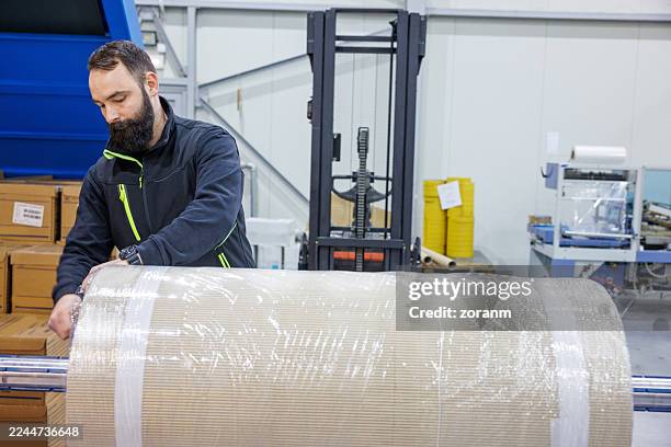 man working in production and distribution industry, unwrapping bale for processing - dielectric stock pictures, royalty-free photos & images
