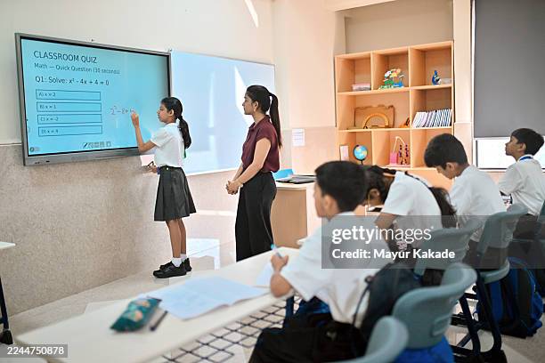 indian schoolgirl solving math problem on interactive white board - interactive smart board stock pictures, royalty-free photos & images