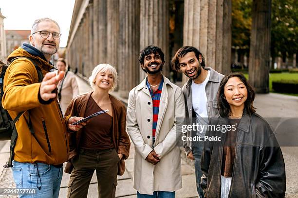 friends standing with travel guide near classical columns at museum island in berlin - indian tour guide stock pictures, royalty-free photos & images