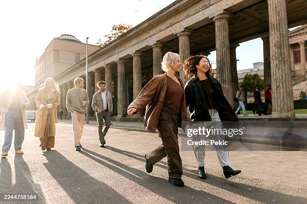 freunde, die in der nähe der klassischen säulen auf der museumsinsel in berlin spazieren gehen und den tag genießen - museumsinsel berlin stock-fotos und bilder