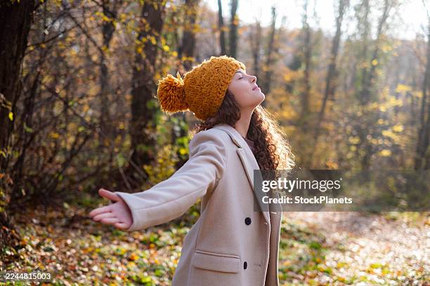 woman enjoying autumn freedom with sun on face - knit hat stock pictures, royalty-free photos & images