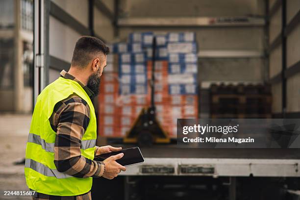 logistics technician reviewing delivery documents on tablet - loading dock stock pictures, royalty-free photos & images