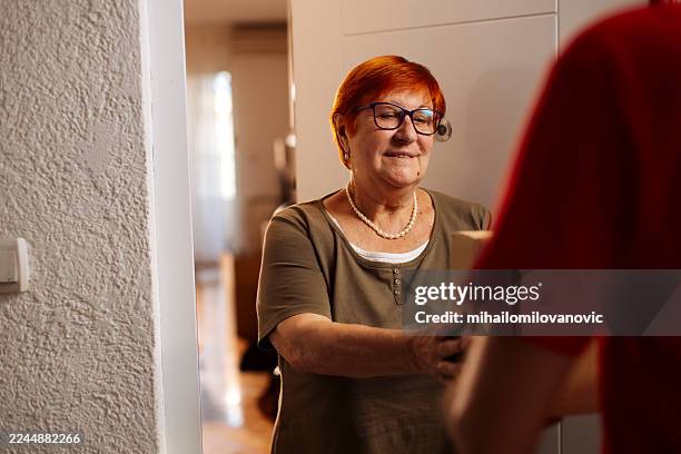 cálido saludo entre la anciana y el repartidor durante la visita a domicilio, sonriente y amigable - entrega sin contacto fotografías e imágenes de stock