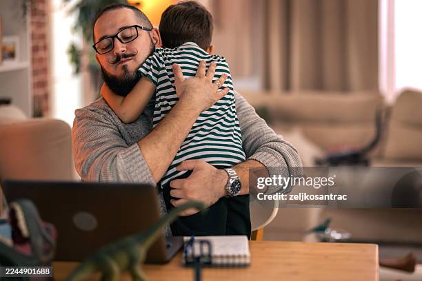 father balancing remote work and parenting responsibilities at home. remote work - distracted stock pictures, royalty-free photos & images