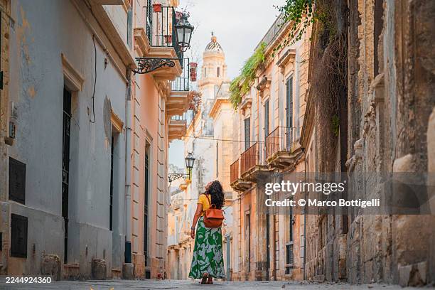 woman strolling a narrow historic street with pastel buildings in lecce, italy - city break stock pictures, royalty-free photos & images