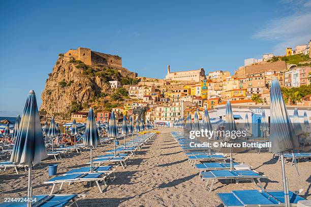 rows of striped blue beach umbrellas in a picturesque hilltop village, scilla, calabria, italy - sun lounger stock pictures, royalty-free photos & images