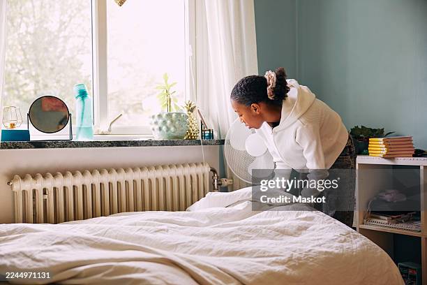 girl making bed in bedroom at home - chambre bien rangée photos et images de collection