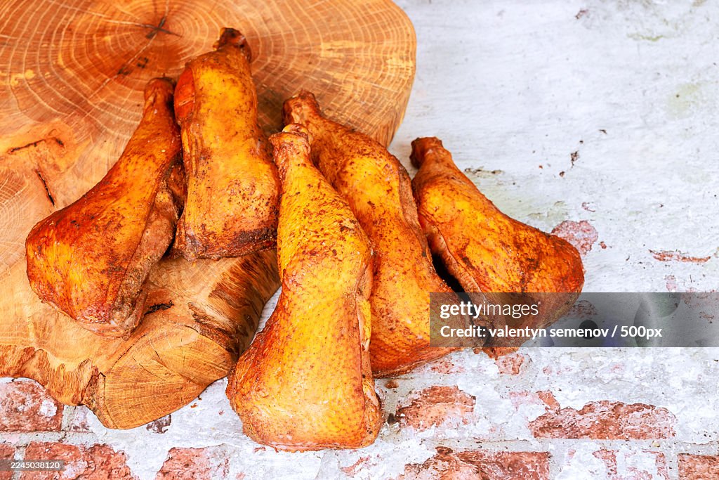 High angle view of smoked chicken meat on a wooden cutting board and rustic table, ready for cooking or serving