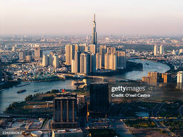 aerial view of a city skyline with tall modern skyscrapers and a winding river at sunset. ho chi minh city, vietnam - ciudad de ho chi minh fotografías e imágenes de stock