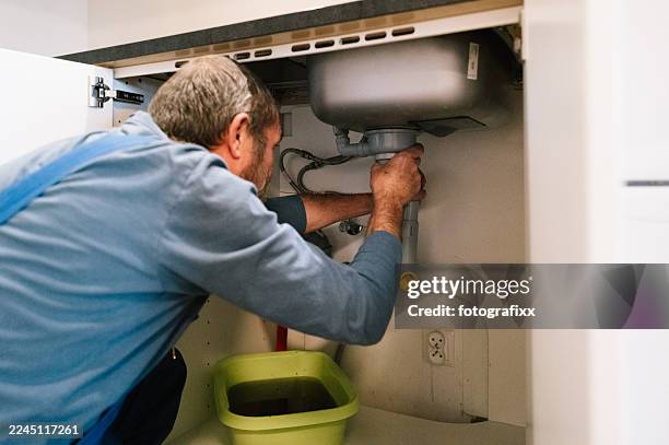 ein klempner repariert einen verstopften abfluss in einer küche - drainage stock-fotos und bilder