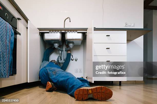 ein klempner repariert einen verstopften abfluss in einer küche - abfluss stock-fotos und bilder