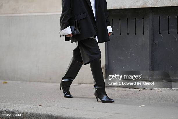 Emy Venturini wears a black oversized blazer jacket by The Frankie Shop layered over a white cotton shirt by Louis Vuitton, black tailored...