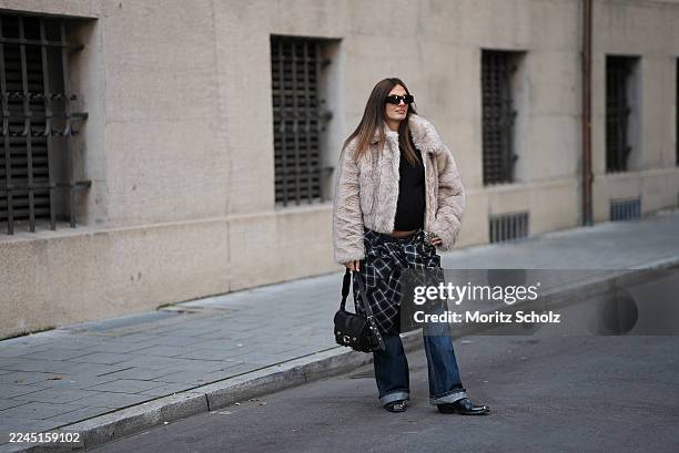 Anna Winter is seen wearing a cropped beige faux fur jacket with a voluminous collar by Stand Studio; a black fitted ribbed top by Comma; a black and...