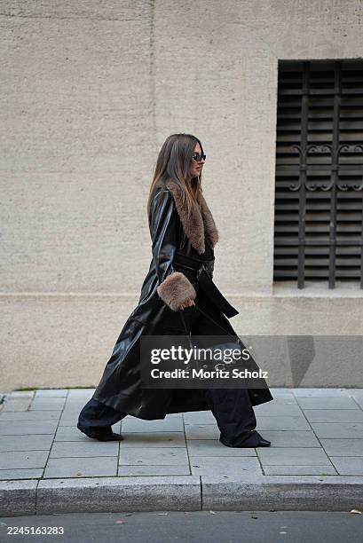 Anna Winter is seen wearing a long black faux leather trench coat with a belted waist and faux fur shawl collar and cuffs by Stand Studio; black...