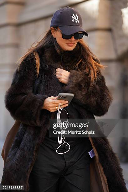 Anna Winter is seen wearing a long dark brown calfskin and fur coat with a wide collar and relaxed fit by Gant; a fitted black top by Comma; black...