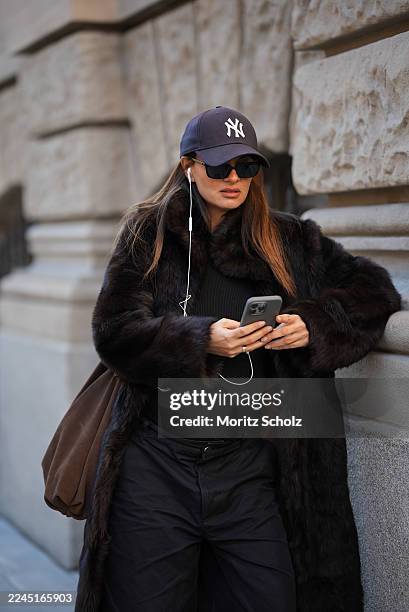 Anna Winter is seen wearing a long dark brown calfskin and fur coat with a wide collar and relaxed fit by Gant; a fitted black top by Comma; black...