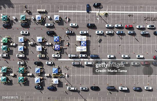 In an aerial view, workers and volunteers help distribute food boxes to those in need at a large-scale drive-through food distribution, in response...