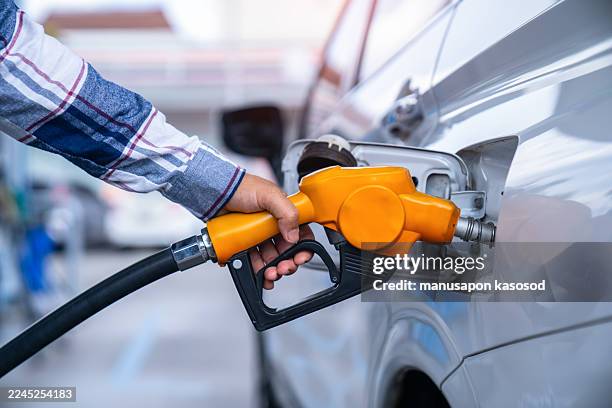 man filling up car with petrol, close-up - bomba de combustible fotografías e imágenes de stock