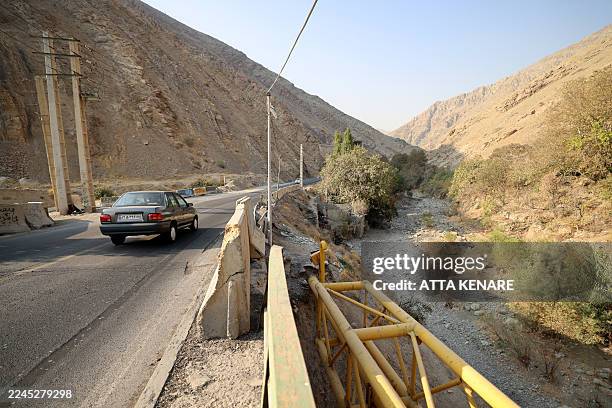 Car drives past he dried-up Kan River, west of Tehran on November 9 as the Iran faces sever water shortages. Iran was laying plans on November 8 to...